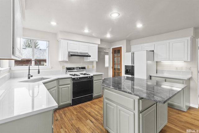 kitchen featuring sink, gas range, a center island, gray cabinets, and white refrigerator with ice dispenser