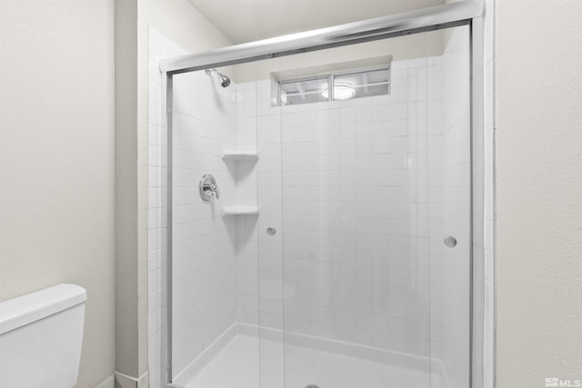 bathroom with a shower with door and toilet