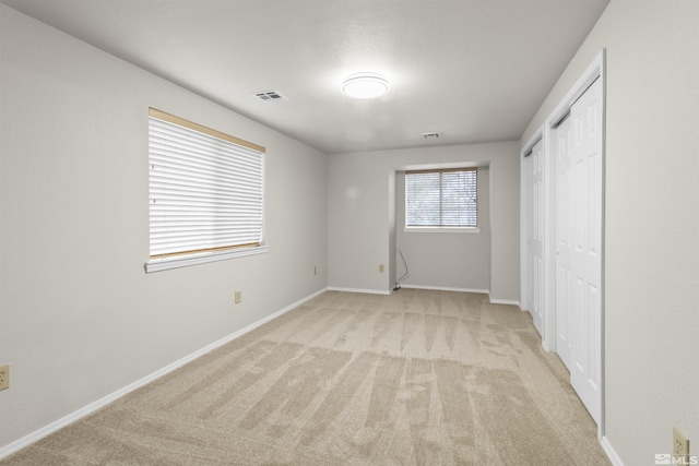 unfurnished bedroom with light carpet and a closet