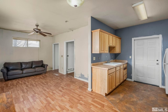 kitchen with light brown cabinetry, sink, light hardwood / wood-style flooring, baseboard heating, and ceiling fan