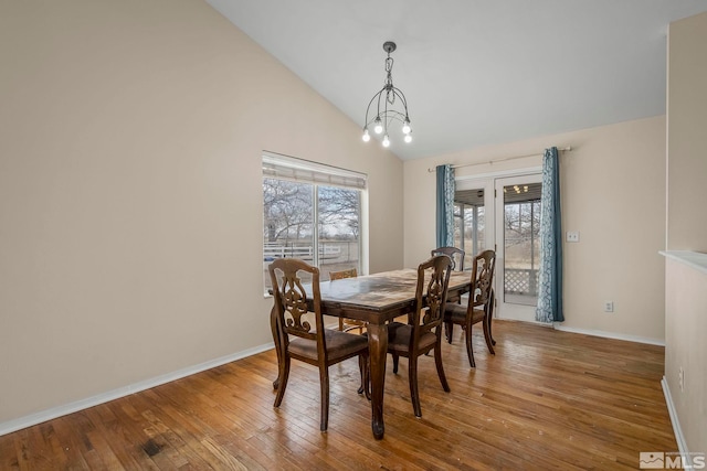 dining area with vaulted ceiling, hardwood / wood-style floors, and a chandelier