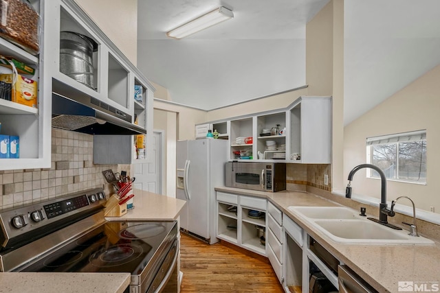 kitchen featuring appliances with stainless steel finishes, lofted ceiling, sink, light stone counters, and light hardwood / wood-style floors