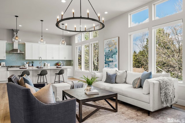 living room featuring a high ceiling, sink, and light wood-type flooring