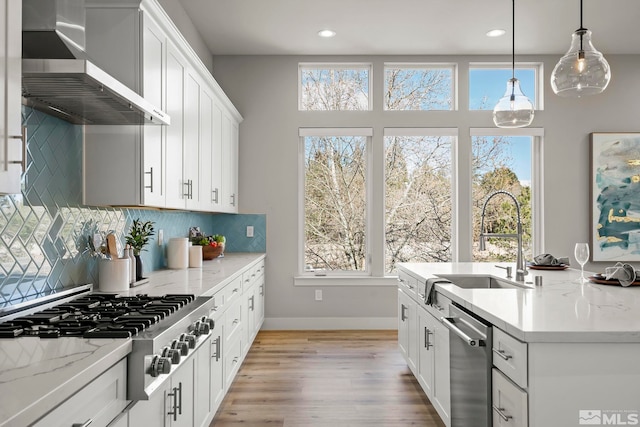 kitchen with white cabinetry, hanging light fixtures, stainless steel appliances, and wall chimney exhaust hood