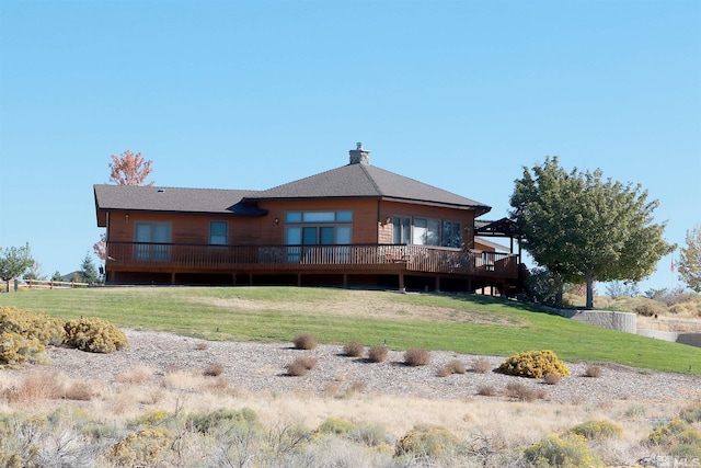 back of property with a deck and a lawn