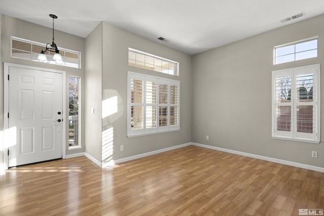 foyer with an inviting chandelier, a wealth of natural light, and light hardwood / wood-style floors