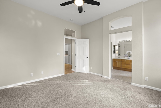 unfurnished bedroom with connected bathroom, light colored carpet, and ceiling fan