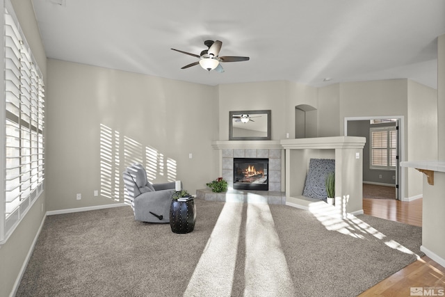 living room featuring a tile fireplace, wood-type flooring, and ceiling fan