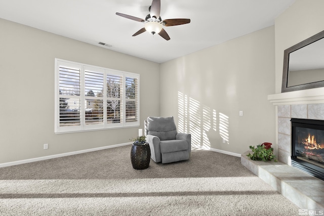 living area with ceiling fan, carpet flooring, and a fireplace