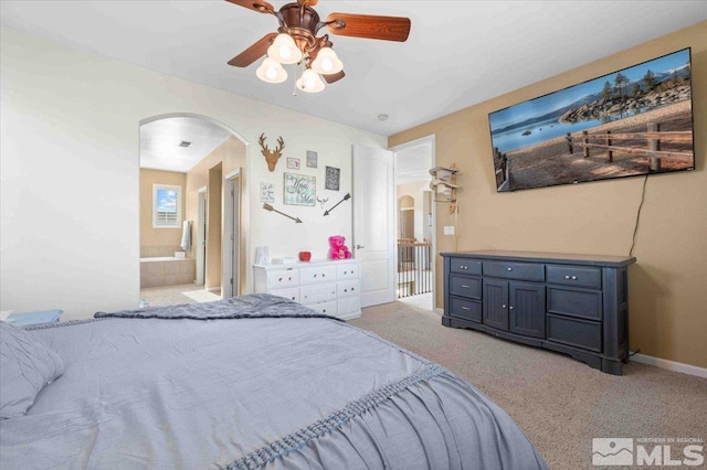 bedroom featuring ceiling fan, ensuite bath, and light carpet