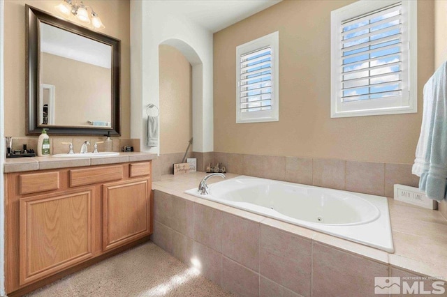 bathroom featuring vanity and tiled bath