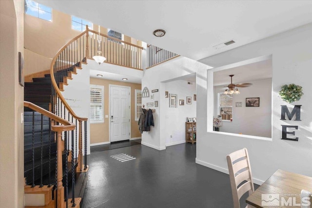 entryway with a healthy amount of sunlight, ceiling fan, and a towering ceiling