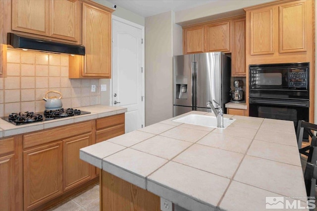 kitchen featuring extractor fan, sink, a center island with sink, tile counters, and black appliances