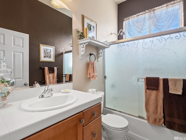 full bathroom featuring vanity, combined bath / shower with glass door, and toilet