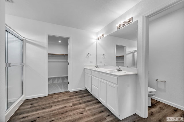 bathroom featuring a shower with door, wood-type flooring, vanity, and toilet