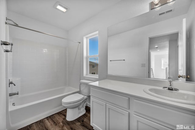 full bathroom with vanity, hardwood / wood-style floors, tiled shower / bath combo, and toilet