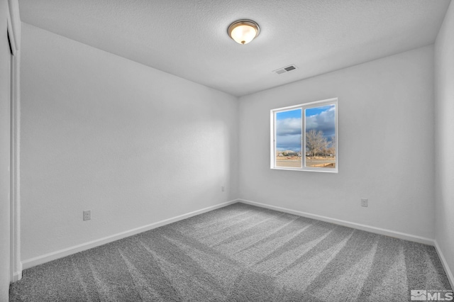 empty room featuring a textured ceiling and carpet