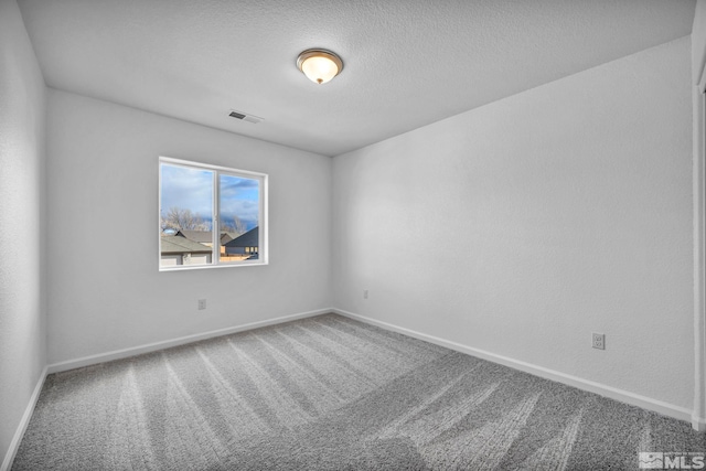 empty room with a textured ceiling and carpet flooring