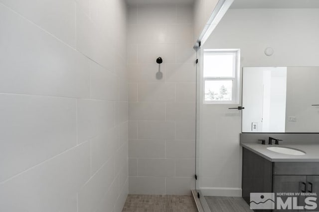 bathroom with tiled shower and vanity