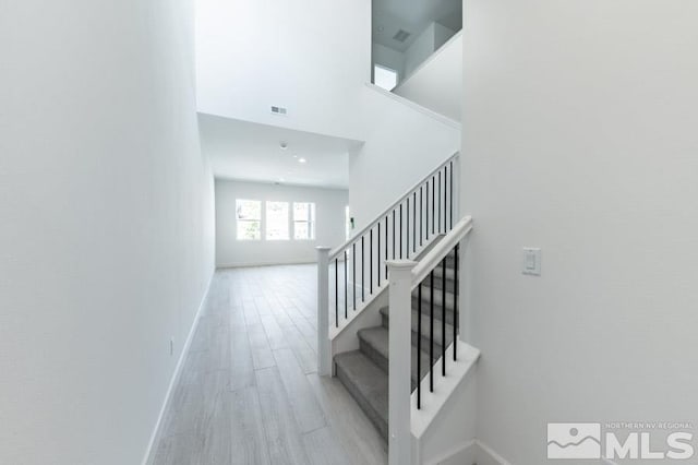 staircase with hardwood / wood-style flooring and a high ceiling