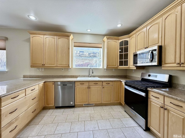 kitchen with stainless steel appliances, sink, light brown cabinets, and light stone counters