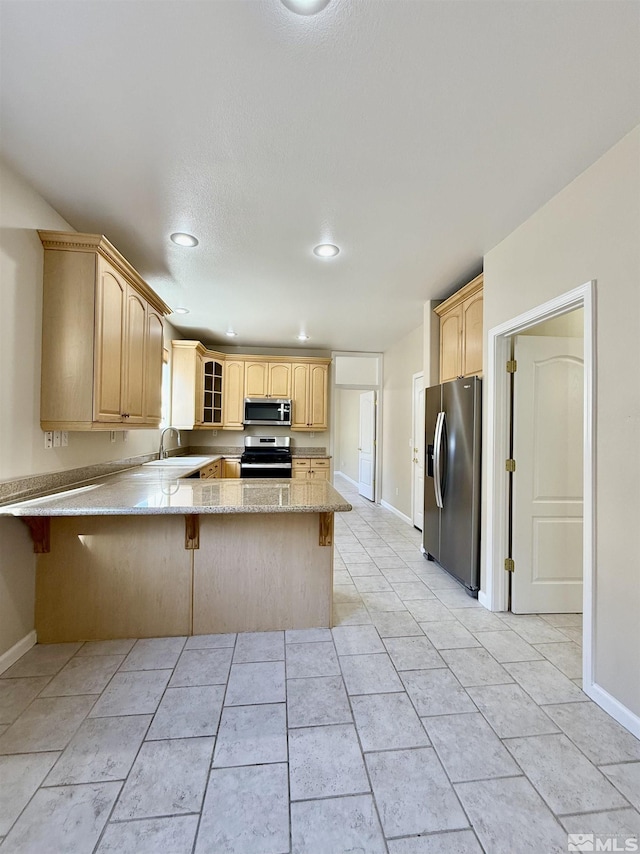 kitchen featuring light brown cabinetry, stainless steel appliances, kitchen peninsula, and a breakfast bar