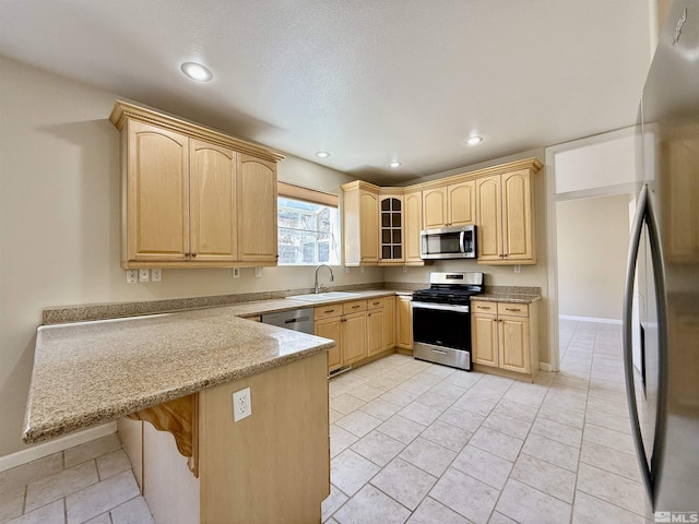 kitchen featuring sink, light brown cabinets, a kitchen breakfast bar, kitchen peninsula, and stainless steel appliances