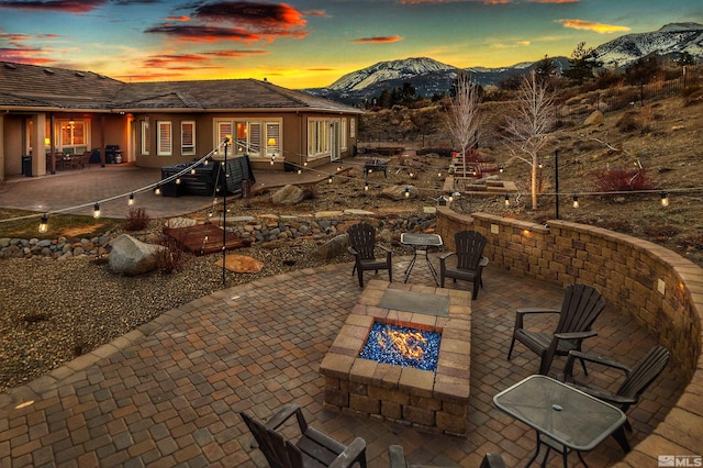 patio terrace at dusk with french doors, an outdoor fire pit, and a mountain view