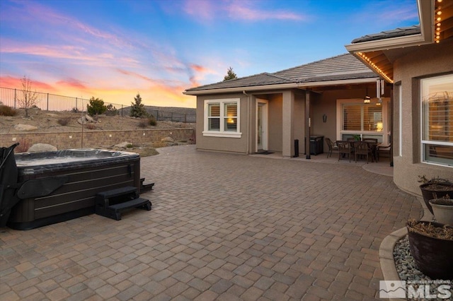 patio terrace at dusk featuring a hot tub