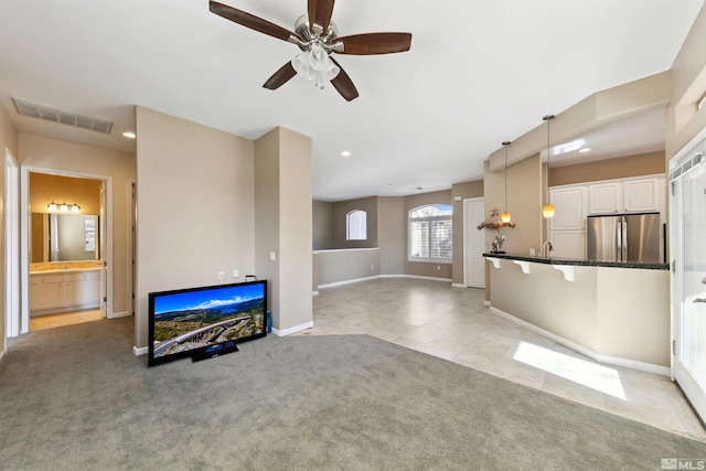 unfurnished living room with sink, light colored carpet, and ceiling fan