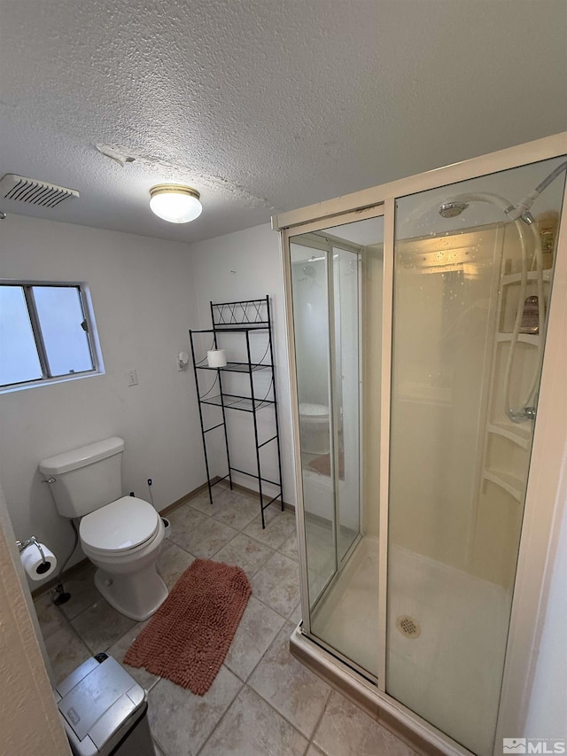 full bath with a textured ceiling, toilet, visible vents, tile patterned flooring, and a shower stall