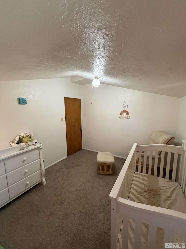 carpeted bedroom with a crib, baseboards, and a textured ceiling