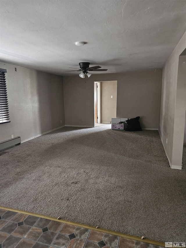 spare room with baseboards, dark colored carpet, a ceiling fan, and baseboard heating