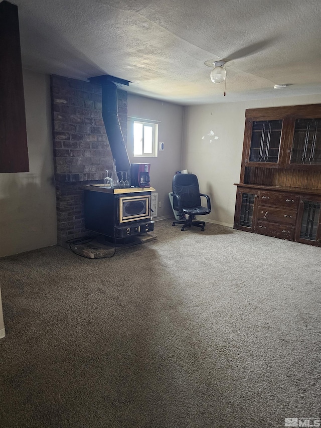 interior space with ceiling fan, carpet floors, a textured ceiling, and a wood stove