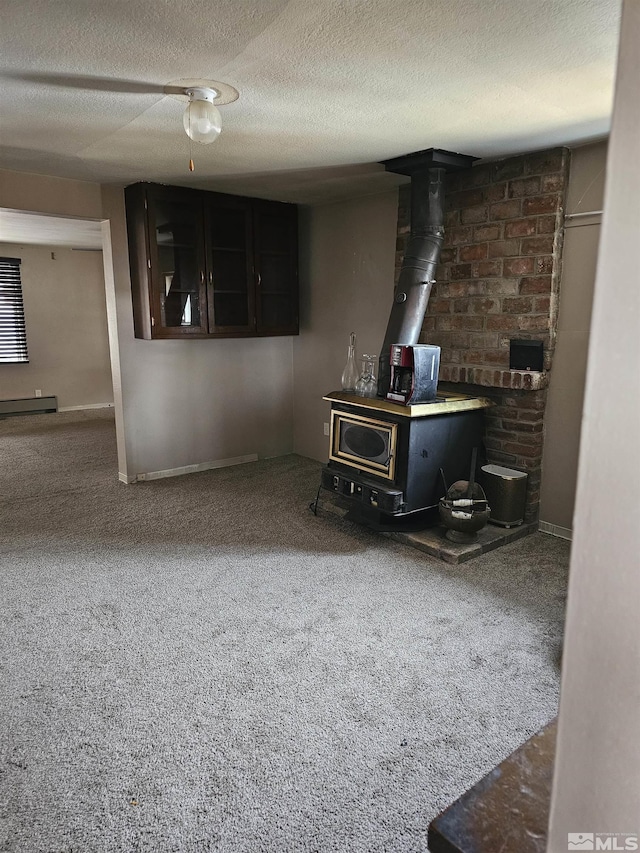living room featuring a baseboard heating unit, carpet floors, a textured ceiling, and a wood stove