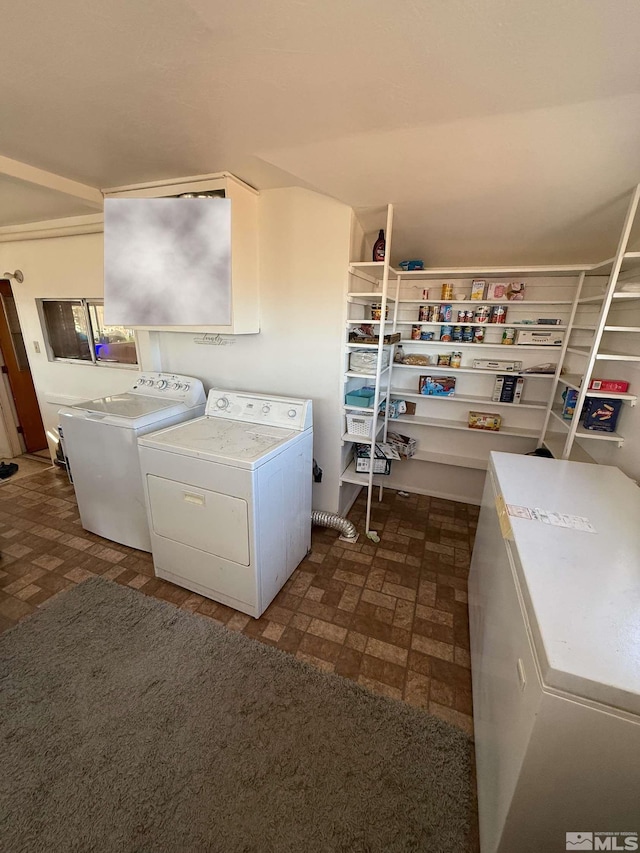washroom with brick patterned floor, washer and dryer, and laundry area