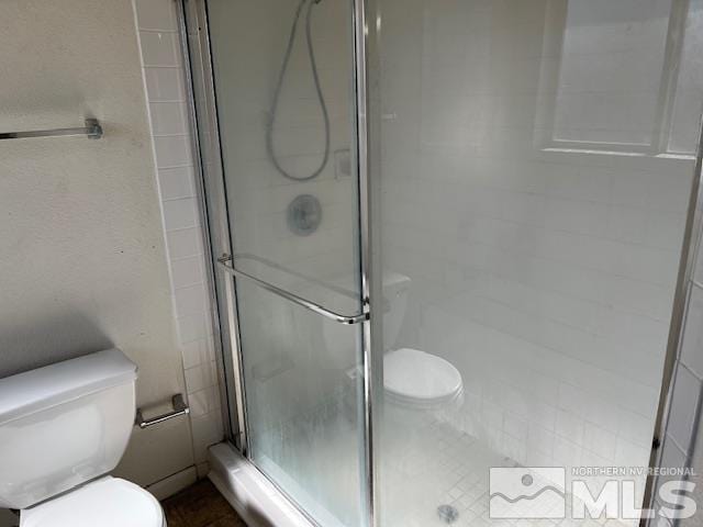 bathroom with toilet and an enclosed shower