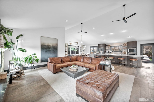 living room featuring ceiling fan, light hardwood / wood-style flooring, high vaulted ceiling, and a healthy amount of sunlight