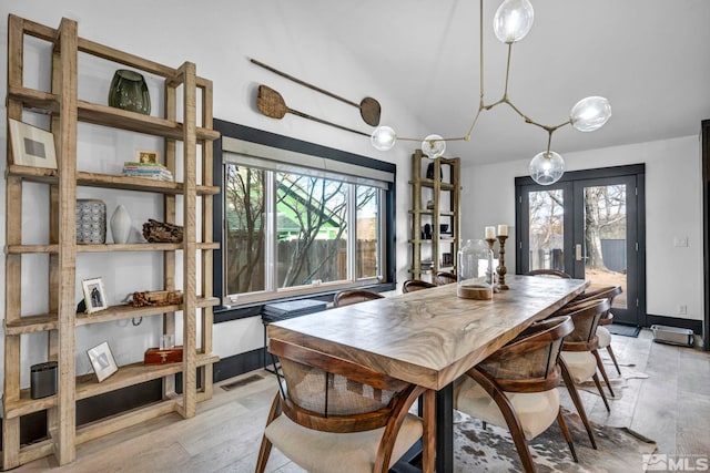 dining space featuring french doors, lofted ceiling, and light hardwood / wood-style flooring