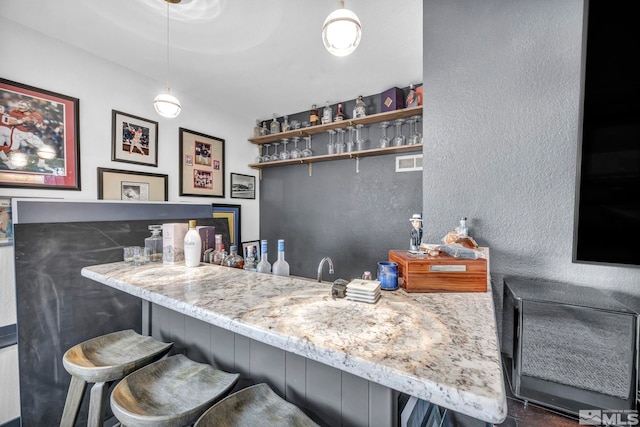 bar featuring light stone countertops and decorative light fixtures