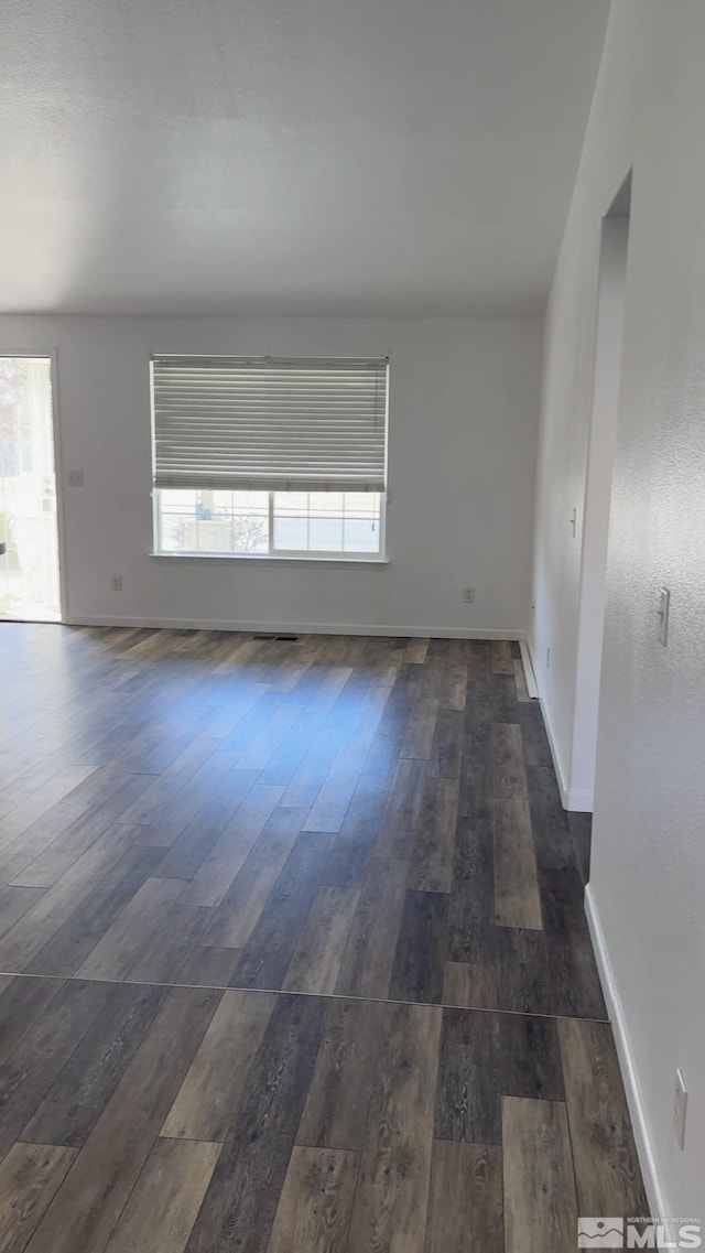 unfurnished room featuring a healthy amount of sunlight and dark hardwood / wood-style floors