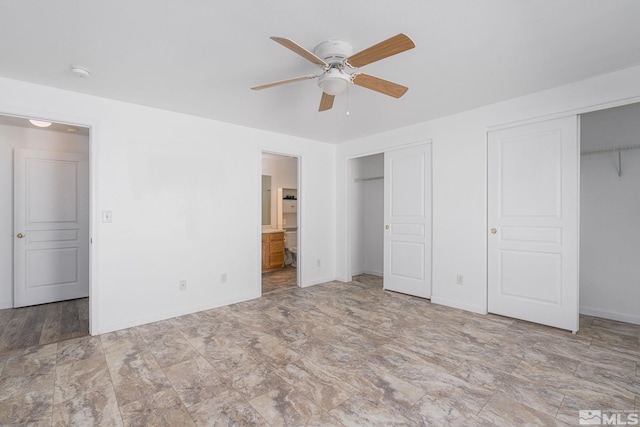 unfurnished bedroom with multiple closets, ensuite bath, and ceiling fan