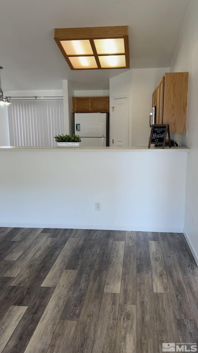 kitchen featuring white refrigerator, dark hardwood / wood-style floors, and kitchen peninsula