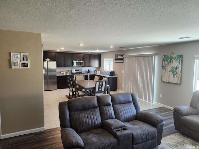 living room featuring sink, a textured ceiling, and light wood-type flooring