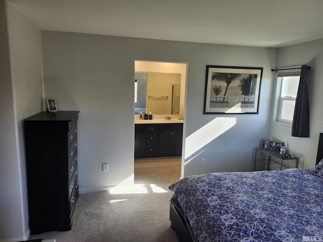 bedroom with light colored carpet, sink, and ensuite bath