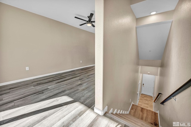 stairs with hardwood / wood-style floors and ceiling fan