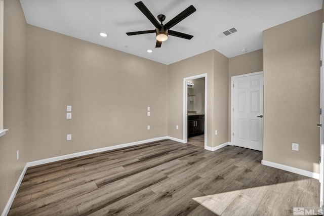 unfurnished bedroom featuring hardwood / wood-style flooring, ceiling fan, and ensuite bath