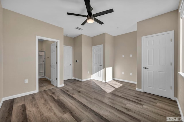 unfurnished bedroom featuring wood-type flooring, connected bathroom, and ceiling fan