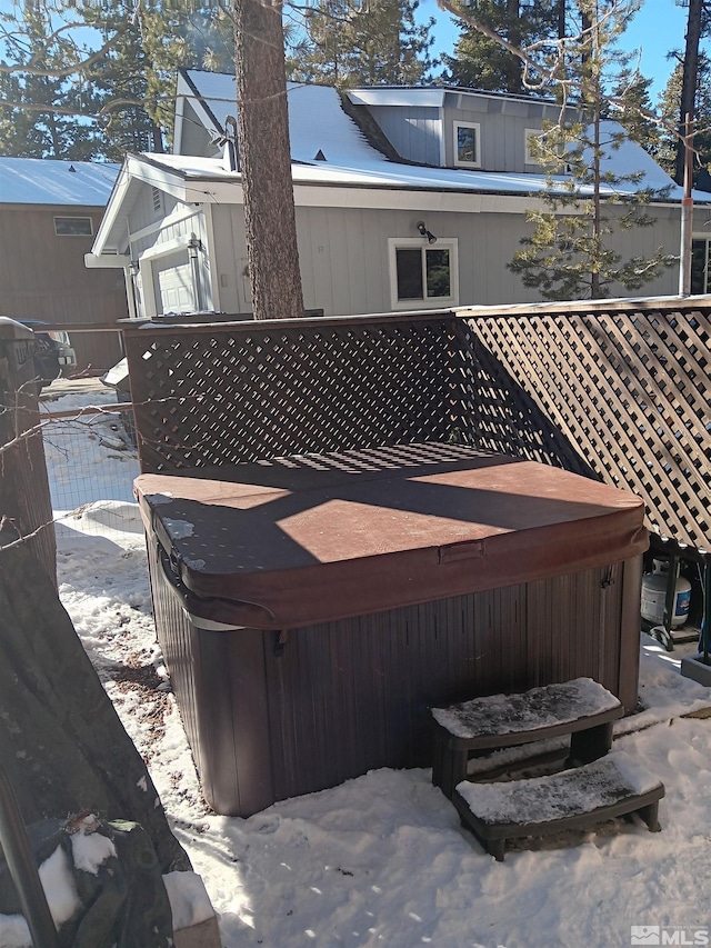 snow covered rear of property featuring a hot tub