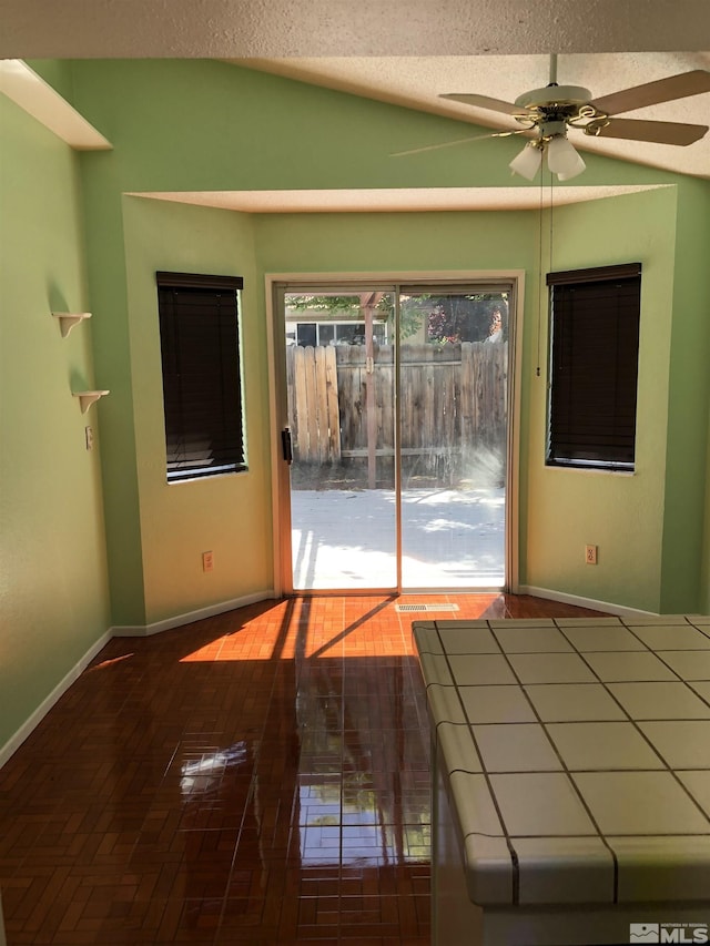 empty room featuring ceiling fan, vaulted ceiling, and a textured ceiling